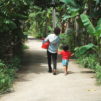 Nainen ja lapsi kävelevät tietä pitkin joulukassiavustus mukanaan.