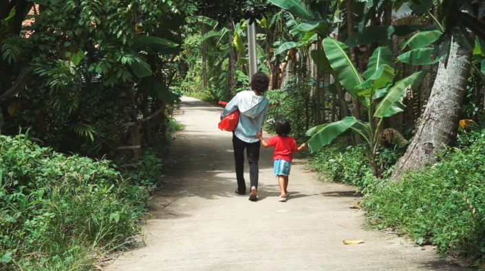 Nainen ja lapsi kävelevät tietä pitkin joulukassiavustus mukanaan.