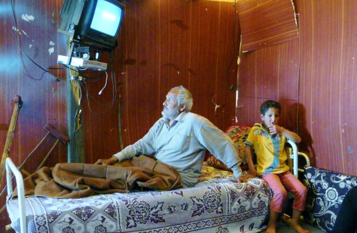 Vanha mies ja poika katsovat tv:tä pakolaisleirillä Libanonissa.