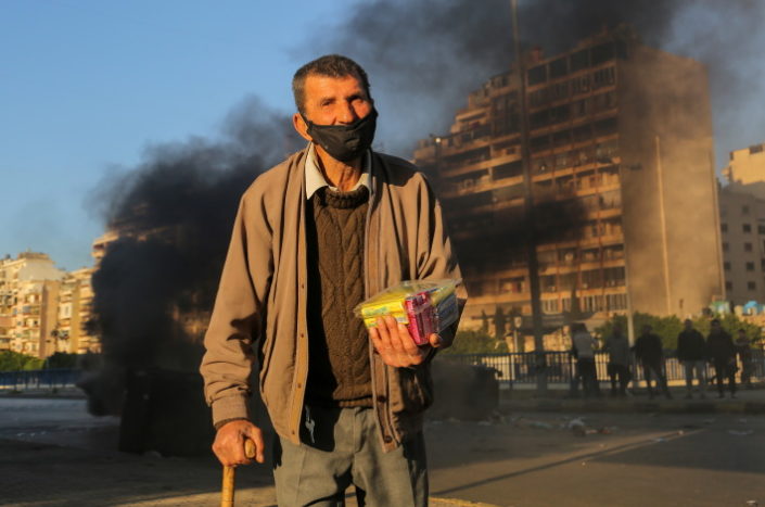 Köyhä mies ja savuava katu Libanonissa.