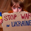 Lapsella on kyltti, joka pyytää lopettamaan sodan Ukrainassa.