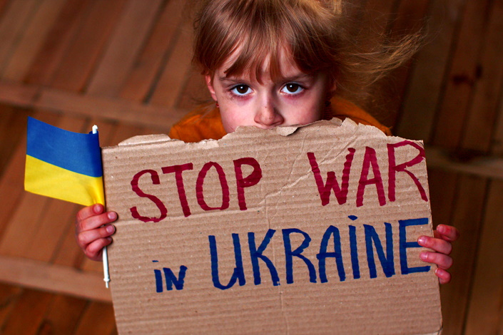 Lapsella on kyltti, joka pyytää lopettamaan sodan Ukrainassa.