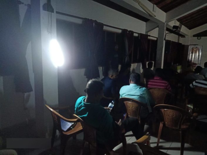 Ihmisiä opiskelemassa Raamattua pimeässä huoneessa sähkökatkon aikana