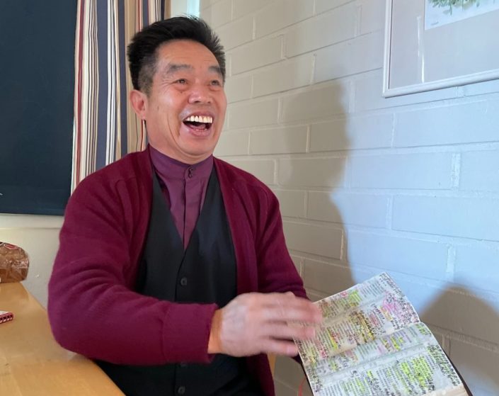 Aasialainen-mies-nauraa-ja-pitää-kädessään-Raamattua