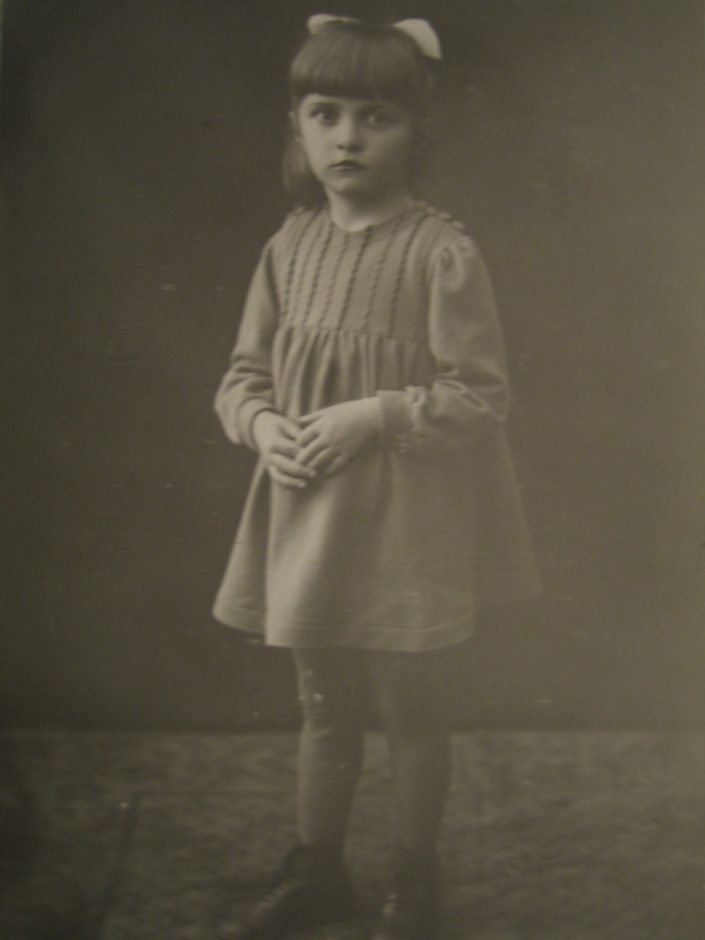 Anja Nurminen seisoo yksin totinen ilme kasvoillaan mustavalkoisessa valokuvassa viisivuotiaana.