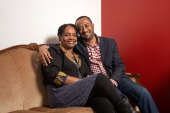 Etiopialainen pariskunta istuu sohvalla ja hymyilee.