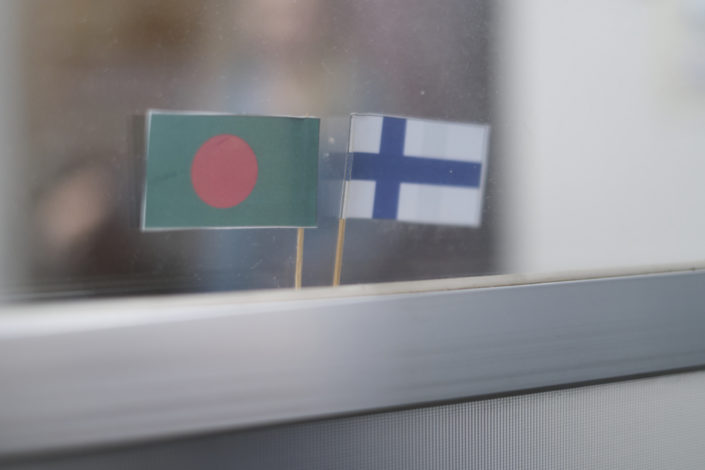 Pieni Bangladeshin lippu ja Suomen lippu vierekkäin ikkunassa.