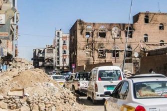 Raunioitunut katunäkymä Jemenistä. Kadulla paljon autoja.