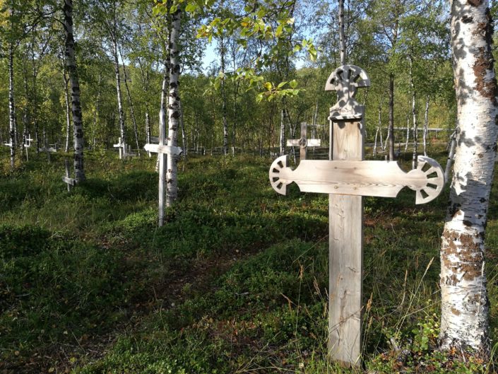 Kuva Utsjoen hautausmaan puisista risteistä nurmihautojen päällä.