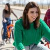 Nainen pyöräilee toisten kanssa ja hymyilee