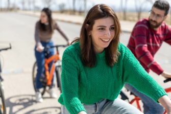 Nainen pyöräilee toisten kanssa ja hymyilee