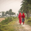 Kaksi tyttöä kävelee tietä pitkin punaisissa asuissa.