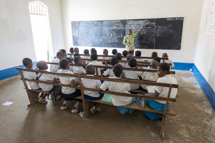 Kongolaisia lapsia koulussa. He istuvat luokassa pulpettirivissä.