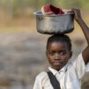 Kongolainen lapsi pitää astiaa päänsä päällä. Astiassa on kengät.