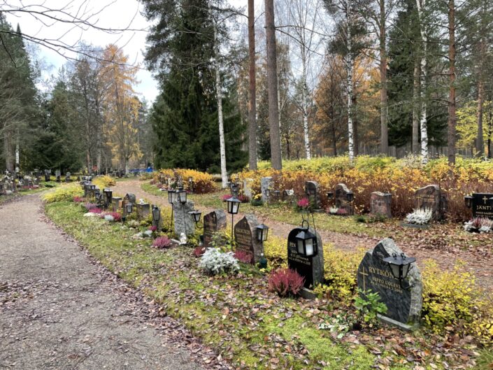 hiekkatie, jota reunustaa rivistö hautakiviä, syksyinen luonto