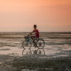 Poika ajaa polkupyörällä auringonlaskussa.