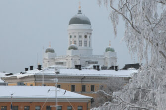 talvinen kuva valkoisesta kirkosta, joka näkyy kuvassa taka-alalla. Edessä muita rakennuksia.