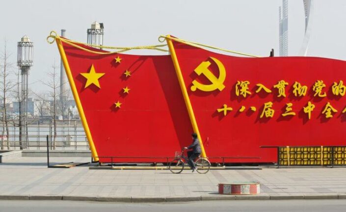 Kaksi suurta punaista lipun mallista seinämää kadulla, molemmat Kiinan lipun tyylisiä. Lipuissa lukee kiinaksi propagandalauseita.