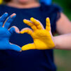 Ukrainan lipun väreillä maalatut kädet muodostavat sydämen.
