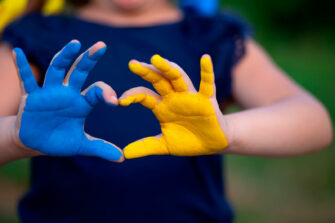 Ukrainan lipun väreillä maalatut kädet muodostavat sydämen.