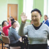 Mongolialainen nainen vilkuttaa iloisesti muiden vammaisten henkilöiden kanssa.