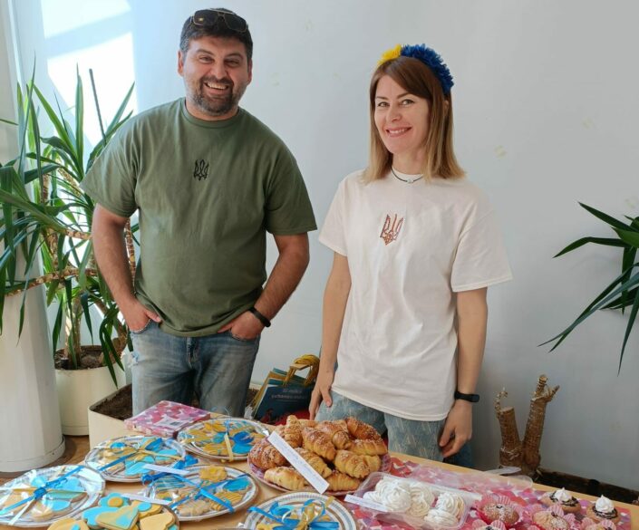 Katetun kahvipöydän äärellä seisoo ukrainalaispariskunta. Ukrainalaiset Stanislav ja Julia Bekher auttoivat talkoolaisina Pieksämäen lähetystorilla ja kahvilassa. Kuva: Sari Sormunen