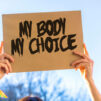 Kädet pitelevät paperia, jossa lukee "my body, my choice".