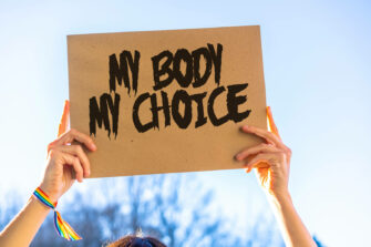 Kädet pitelevät paperia, jossa lukee "my body, my choice".