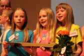 Kolme lasta laulamassa virsikirjat kädessä