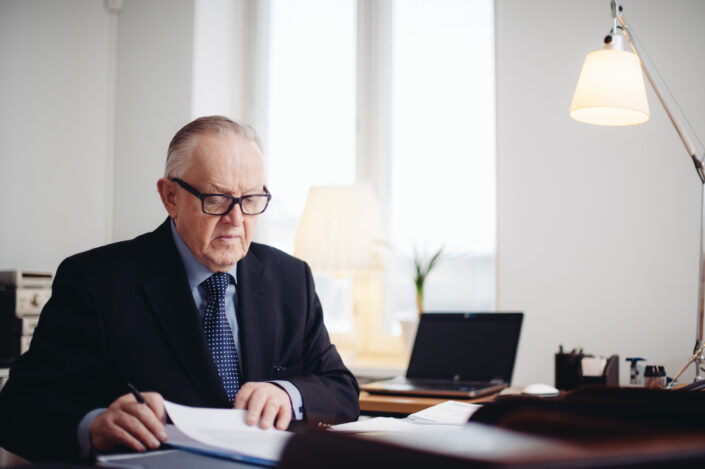 Presidentti Martti Ahtisaari käymässä kirjeenvaihtoa kirjoituspöytänsä takana.