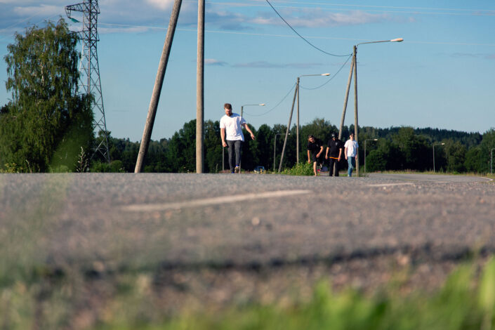 neljä miestä skeittaa maantien laitaa