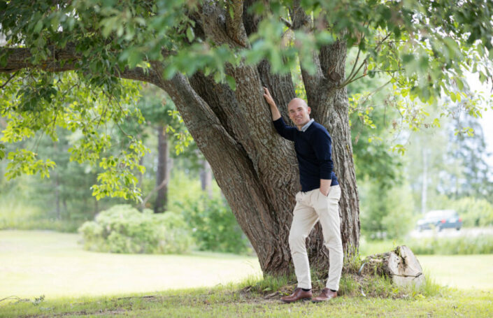 Samuli Korpinen nojaa lehtipuuhun.