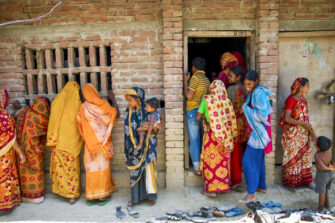 Bangladeshilaisia hymyileviä naisia tiilirakennuksen edessä