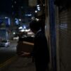 Mies pahvilaatikko kädessä pimeällä kadulla kaupungissa.