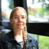 Ulla Barendsen-Riikonen istuu pöydässä ikkunan äärellä. Hänen hiuksensa ovat letillä, ja hänellä on silmälasit.