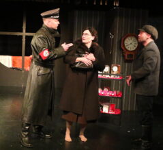Kuvan keskellä seisoo Corrie ten Boom, jota näyttelee Marja Mäkelä. Hänen vieressään on natsisotilas ja toisella puolella mies, joka seuraa tilannetta.