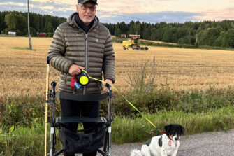 Antero Laukkanen lemmikkikoiransa kanssa pyörätuolissa keltaiseksi värjäytyneen syksyn viljavainion edessä.