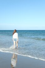 Tyttö seisoo meren rannalla. 