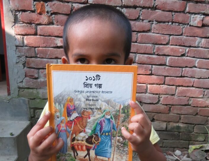Pieni poika pitelee käsissään ja osin kasvojensa edessä lasten kristillistä kirjaa