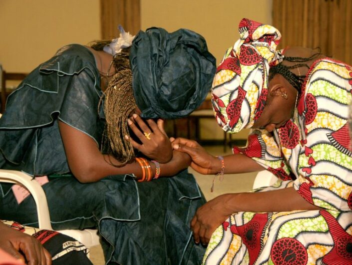 Kaksi afrikkalaista naista kumartuneena rukoukseen.