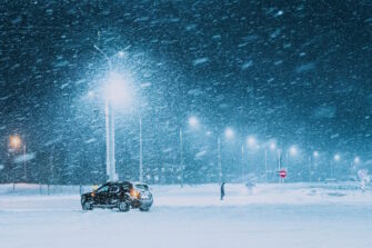 Yksinäinen ihminen ja auto talvimyrskyssä.