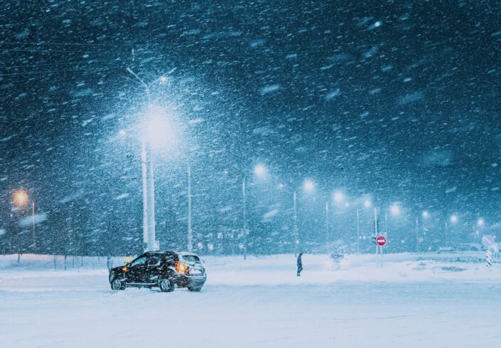 Yksinäinen ihminen ja auto talvimyrskyssä.
