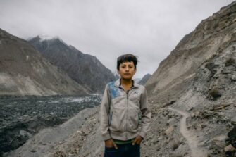 Pakistanilainen poika karussa maastossa vuorten välissä.
