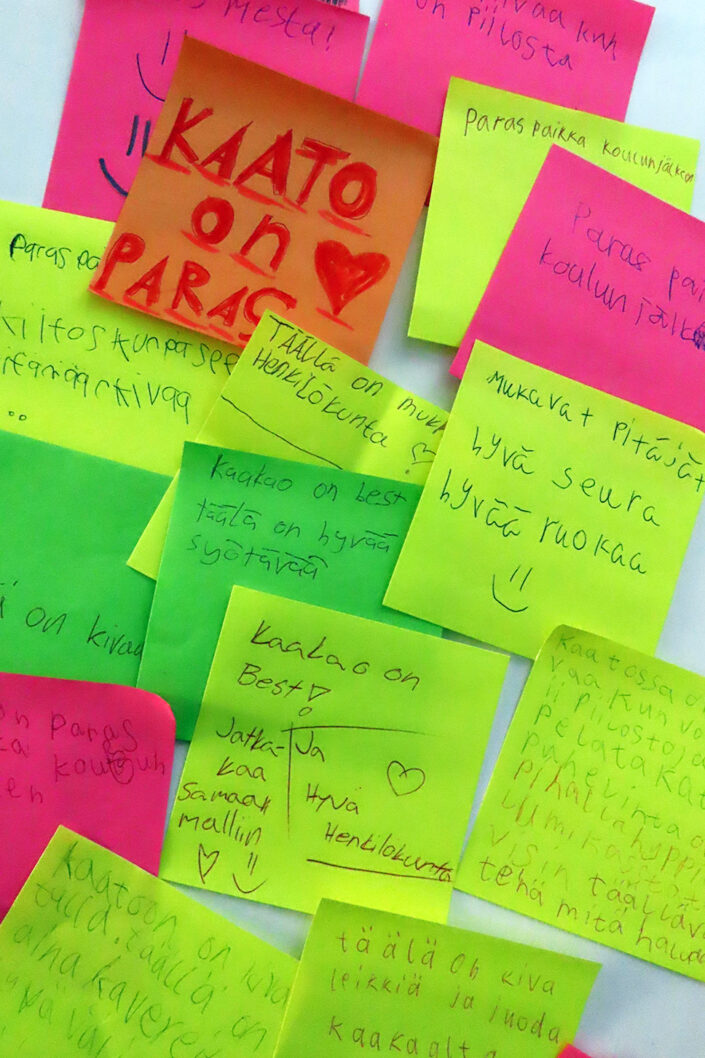 Kuvassa on neonvärisiä post-it-muistilappuja, joille Kaakaotorstaissa käyvät lapset ovat kirjoittaneet terveisiään.