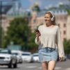 Nainen kesäisessä kaupungissa kuulokkeet korvilla
