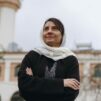 Egyptiläinen naiskristitty seisoo minareetin edessä.
