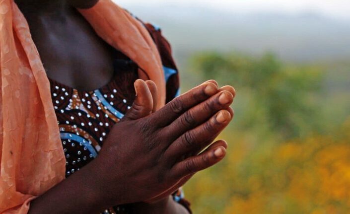 Valokuva afrikkalaisnaisen yhteen liitetyistä käsistä.