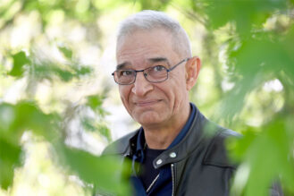 a_man_smiling_and_looking_at_camera_leaves_trees_photo_Saija_Tiilikainen