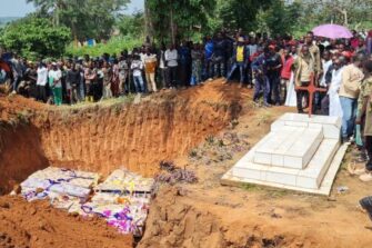 Avoinna oleva joukkohauta, ympärillä paljon afrikkalaisia ihmisiä.