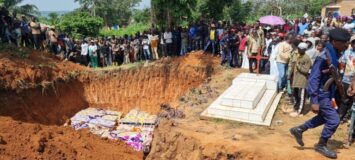 Avoinna oleva joukkohauta, ympärillä paljon afrikkalaisia ihmisiä.